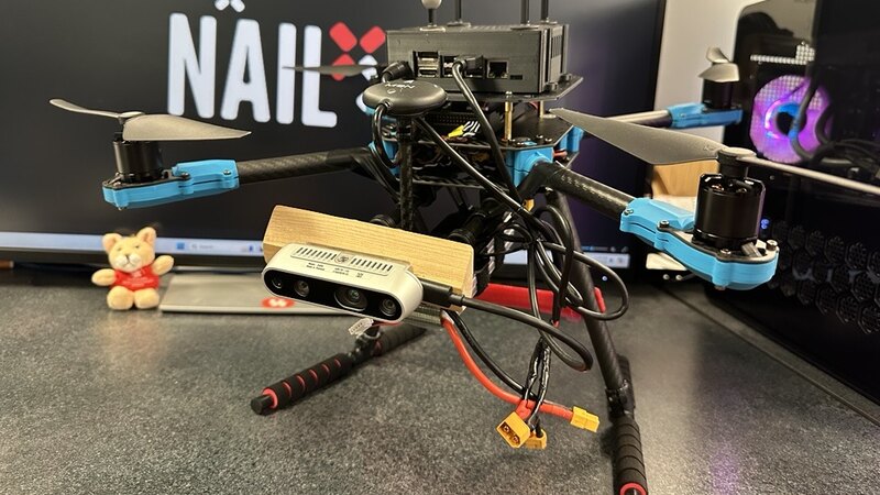 The team's quadrotor with a depth camera and an onboard computer, in front of the NAIL logo.
